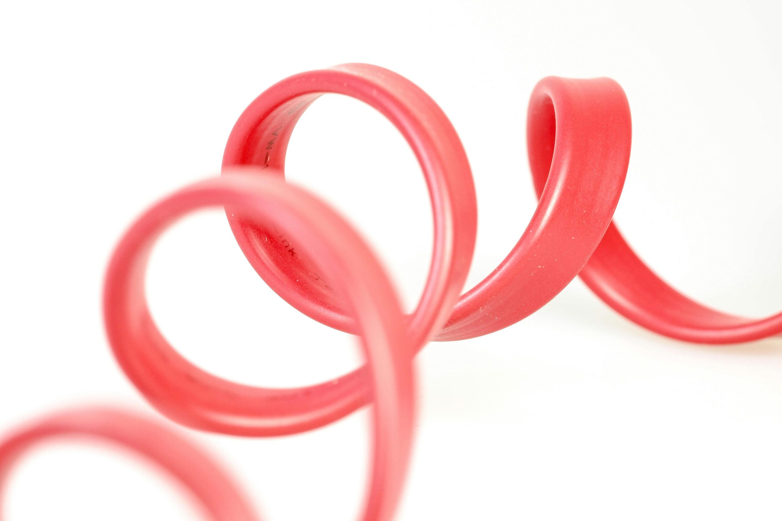 Close-up of a red rubber tube with elegant curves against a white background.